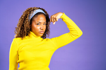 Young woman showing her strength and empowerment on purple background