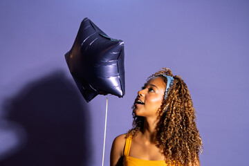 Young woman holding star shaped balloon expressing excitement and joy