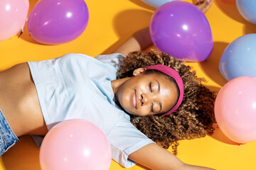 Obraz premium Joyful young woman relaxing among colorful balloons