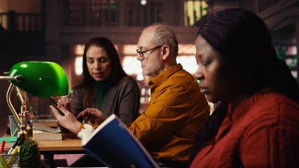 Colleagues disturbing a woman with their loud reading in the library, african american pupil making a noise complaint and being disturbed by the disrespect. Breaking the rules. Camera B.