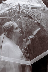 The bride and groom are standing under umbrellas