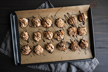 Macaroons Drizzled with Dark Chocolate on a Sheet Pan: Coconut meringue drop cookies dipped in bittersweet chocolate on parchment paper