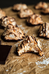 Macaroons Drizzled with Dark Chocolate on Unbleached Parchment Paper: Toasted coconut meringue drop cookies dipped in bittersweet chocolate close-up