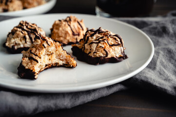 Macaroons Drizzled with Dark Chocolate on a Small Plate: Toasted coconut meringue drop cookies dipped in bittersweet chocolate close-up