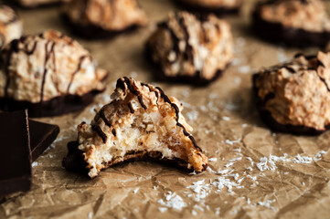 Macaroons Drizzled with Dark Chocolate on Unbleached Parchment Paper: Toasted coconut meringue drop cookies dipped in bittersweet chocolate close-up