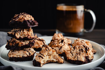 Macaroons Drizzled with Dark Chocolate on a Small Plate: Toasted coconut meringue drop cookies dipped in bittersweet chocolate close-up