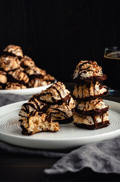 Macaroons Drizzled with Dark Chocolate on a Small Plate: Toasted coconut meringue drop cookies dipped in bittersweet chocolate close-up