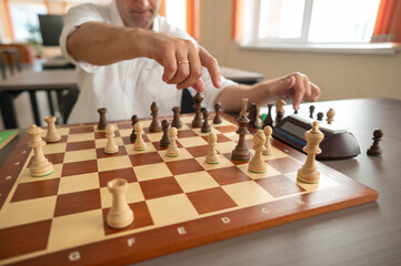 Close up of hands of middle aged caucasian man playing chess. 