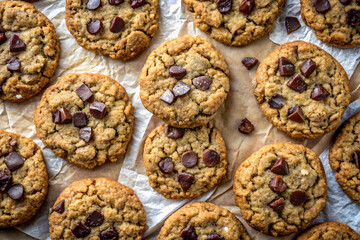 A batch of oatmeal chocolate chunk cookies with sea salt on parchment paper