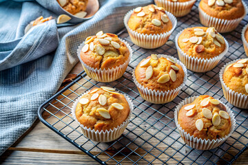 Almond-topped muffins cooling on a wire rack with a cloth napkin nearby