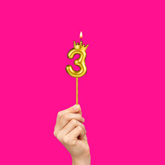 Hands holding number-shaped candles - Birthday number 3