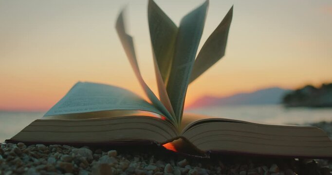 Open book on beach with flipping pages at golden sunset in Makarska Croatia