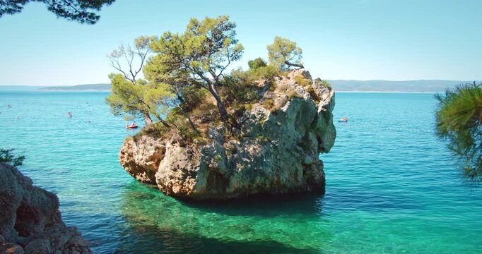 Rocky island covered with pines rises from clear sea waters in Brela Croatia