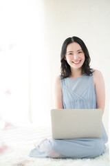 パソコンの前のかわいいカメラ目線の女性　春夏のノースリーブ白バック...