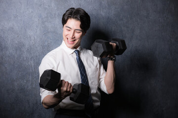 ダンベルで筋トレするスーツの男性...