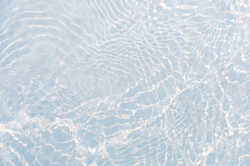 Blue water with ripples on the surface. Defocus blurred transparent blue colored clear calm water surface texture with splashes and bubbles. Water waves with shining pattern texture background.