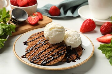 Tasty Dutch waffles (stroopwafels) with ice cream and chocolate sauce on white table, closeup