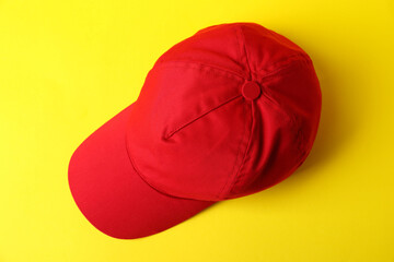 Red baseball hat on yellow background, top view. Mockup for design
