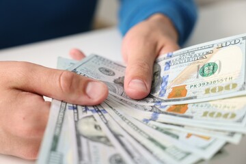 Man counting money at white table, closeup
