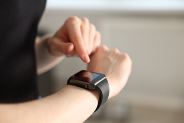 Woman checking fitness tracker during training indoors, closeup. Space for text