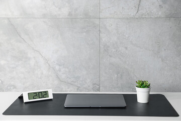 Stylish workplace with laptop and black mousepad on white table indoors. Space for text
