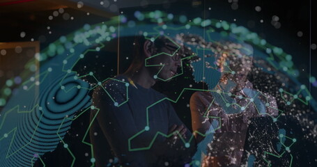 Examining network map, two tech professionals in business attire viewing holographic globe in lab