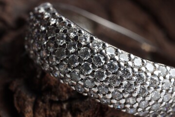 Ring with beautiful shiny diamonds on wood, macro view