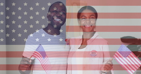 Smiling Black man and Asian woman holding US flags with VOTE badges at home, flag overlay