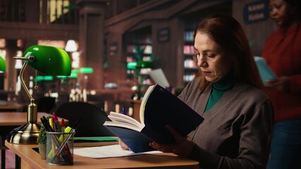Determined woman writing thesis citations from a specialty book at the library, mature learner working toward a higher education goal. Academic materials in a quiet campus study area. Camera A.