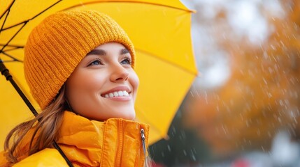 Joyful woman enjoying autumn rain under a bright yellow umbrella