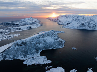 A Stunning Aerial View of Majestic Snowy Mountains and Serene Waters at Beautiful Sunset