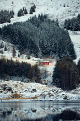 A Serene Snowy Landscape Featuring a Bright Red House and Stunning Reflections Around