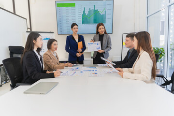 Group of Asian businessmen are analyzing charts and graphs during productive meeting, demonstrating...