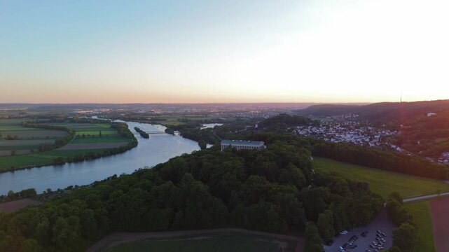 Sunset aerial view of Walhalla memorial on Braeuberg hill near Regensburg, Germany. This neoclassical temple overlooks the Danube River, glowing in golden hour light over the Bavarian landscape. 