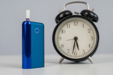 Electronic cigarette and alarm clock on white background. Tobacco heating systems.