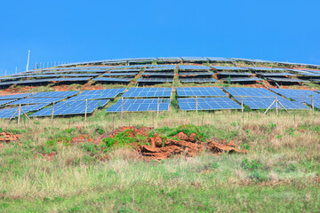 Rows of solar panels stretch across a sunlit hillside, angled to capture maximum sunlight. Scene...