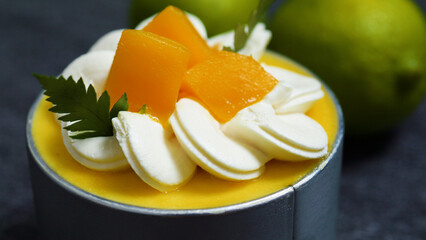 Creamy mango mousse cake topped with whipped cream, fresh mango slices, and parsley, resting on a...