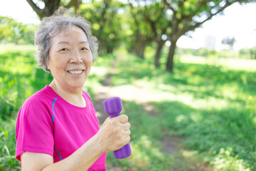Happy Asian senior woman lifting dumbbell