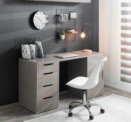 Modern industrial home office with gray wood desk, built-in drawers, black metal grid organizer,...