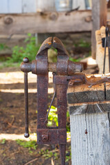 Old rusted vise mounted on wooden post