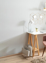 Minimal home office with a white trestle-style desk with warm wooden legs pink velvet accent chair...