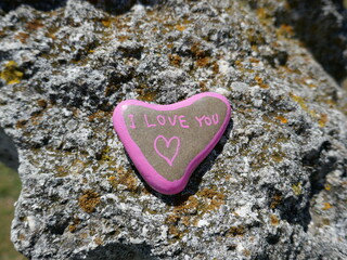 Rough ancient stone surface with I love you heart stone and lichens