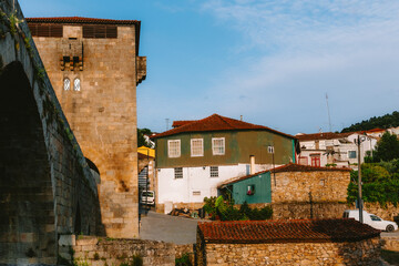 Warm sunlight illuminating the historic stone bridge and charming terracotta roofed houses in the picturesque town of Ucanha, Tarouca, Viseu district, Portugal