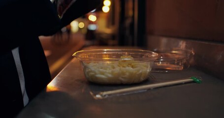 An elegant woman prepares to eat takeaway food while standing on the street of the night city. Close-up of her hands, unrecognizable person