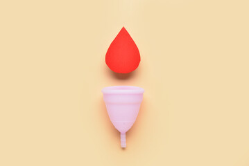 Composition with menstrual cup and blood drop made of paper on beige background