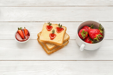 Tasty toasts with sweet strawberry jam and fresh berries on white wooden background