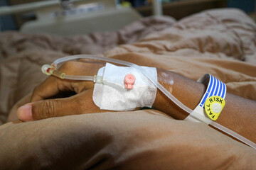 IV or intravenous drip in patient hand and warning of fall risk for patient in hospital