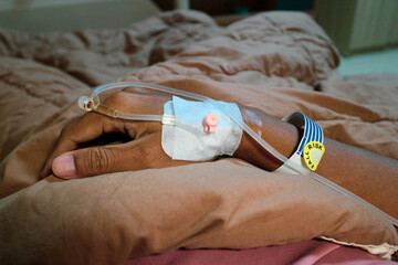 IV or intravenous drip in patient hand and warning of fall risk for patient in hospital