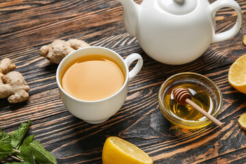 Cup of ginger tea and bowl with honey on wooden background