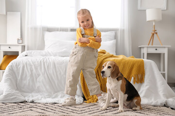 Cute little girl with Beagle dog in bedroom
